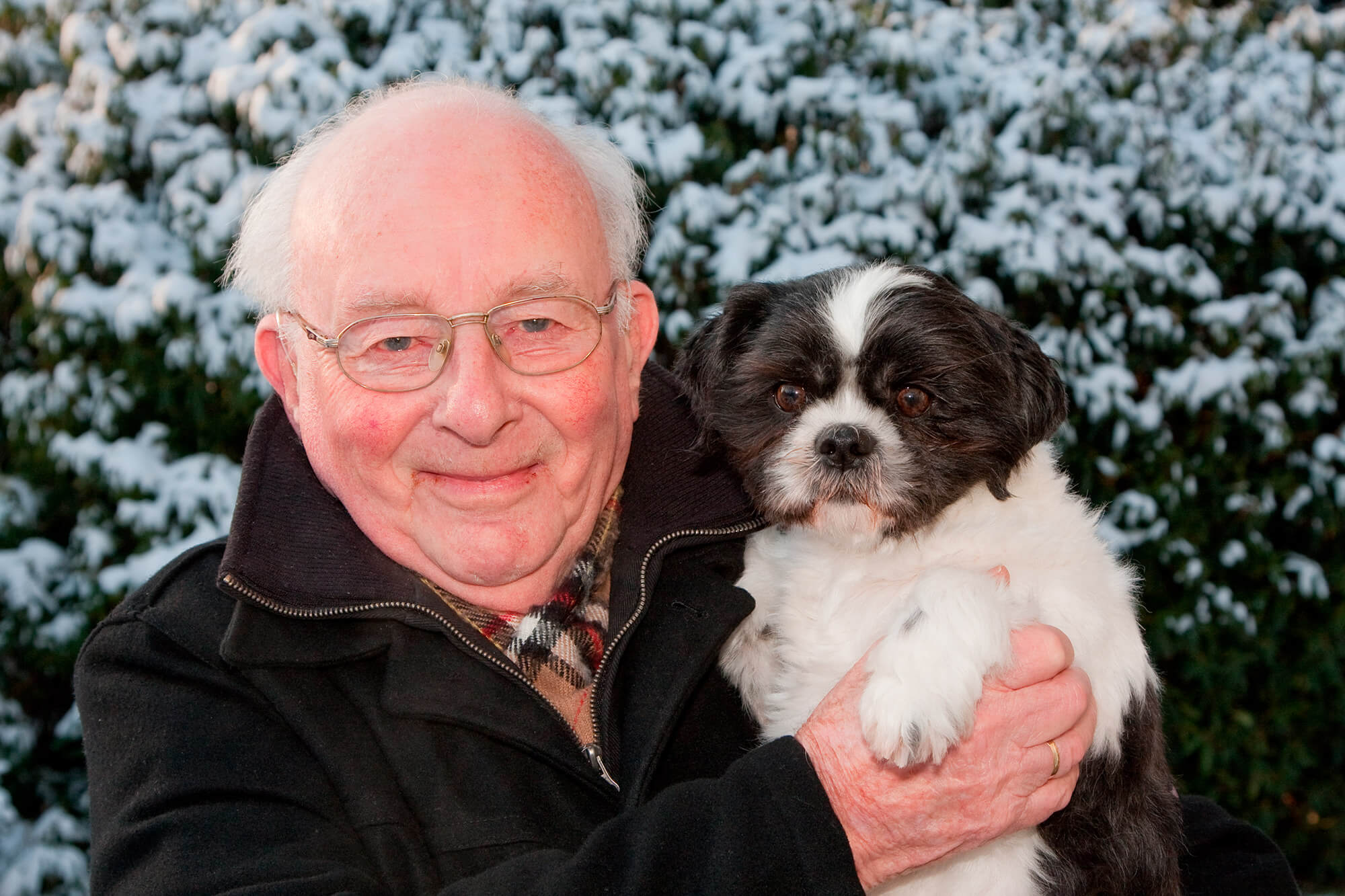 hombre mayor en invierno con perro senior en brazos